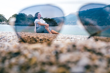 Happy woman on beach through sunglasses lens, enjoying coastal view and peaceful moment