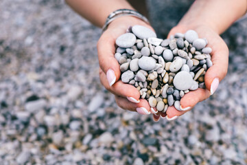 Heart-Shaped Pebbles in Female Hands on Rocky Beach Representing Love, Nature and Calm