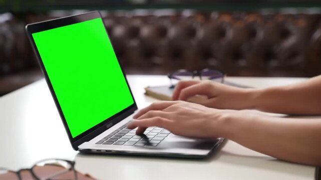 Close Up of Hands Typing on a Laptop with Green Screen Display.