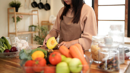 A woman in the kitchen Wear an apron is peeling a pumpkin to cook something delicious.
