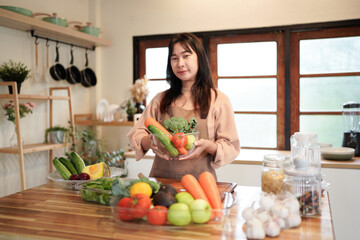 A woman is holding a bowl of vegetables in a kitchen. Concept of health and wellness, as the woman is surrounded by fresh produce