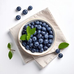 Overhead shot of bowl overflowing with blueberries, mint, on cloth