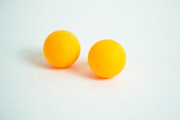 Two bright orange table tennis balls sit side-by-side on a white surface. The simple and clean composition is perfect for concepts of sports, recreation, games, or equipment.

