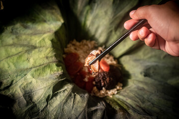 Rice wrapped in lotus leaves with Chinese sausage and shiitake mushrooms on top of the rice.
