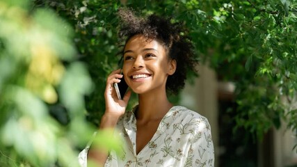 Young Woman on a Call in Nature: A beautiful young woman with a radiant smile, enjoying a phone call amidst lush green foliage and natural light, exuding serenity and contentment. - Powered by Adobe