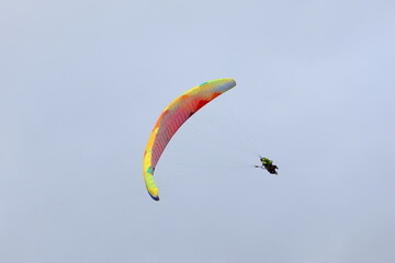 Close-up of two people on a colorful paraglider in the sky, paragliding with assistance, learning paragliding, tandem flight