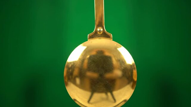 The pendulum of an old grandfather clock swinging slowly and rhythmically, isolated on solid green background grandfather clock, slow, antique