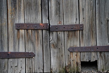 An iron bracket on an old wooden garage and barn door.