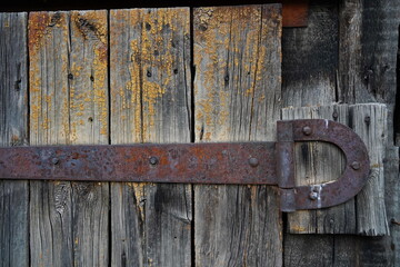 An iron bracket on an old wooden garage and barn door.