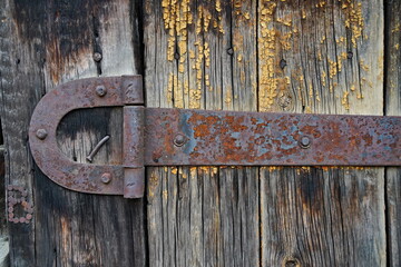 An iron bracket on an old wooden garage and barn door.