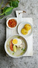 Soto Banjar in a bowl with sambal and potato cake. Selective focus