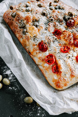 Freshly baked focaccia with cherry tomatoes and olives on a baking tray