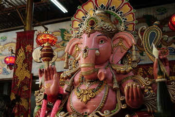 Colorful statue of Lord Ganesha decorated with ornaments and flowers inside temple, symbol of Hindu...