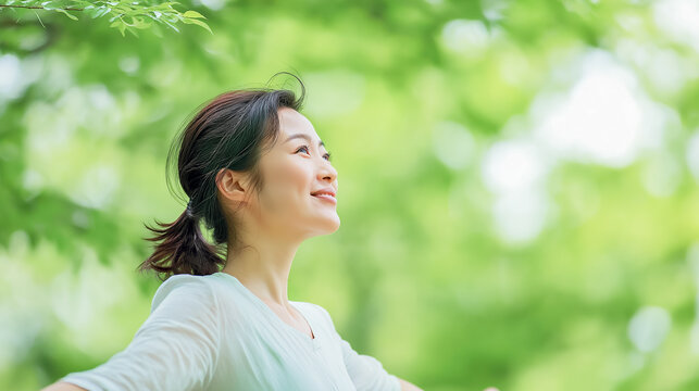 Woman enjoying fresh air in green forest with positive energy and relaxation