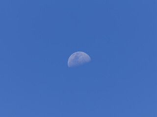 Half moon visible during the daytime in Australia with a clear blue sky background