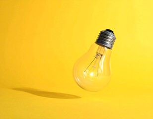 A glass lightbulb suspended on a yellow background