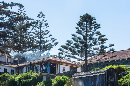 Buildings on the Chilean Pacific coast near Pablo Neruda Beach feature rustic designs with wood and stone materials. 