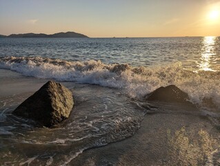 Beach with rocks and waves during sunset
