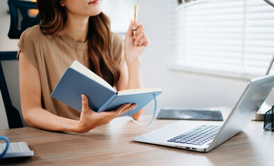 Closeup view of young professional businesswoman writing his idea concepts on notebook while working on his project at office