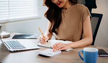 Confident businesswoman in office using calculator and laptop for accounting, finance, and tax report analysis