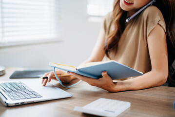 Closeup view of young professional businesswoman writing his idea concepts on notebook while working on his project at office