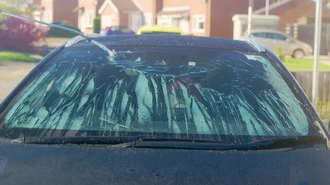 Rinsing windscreen on a black car with protection and instant water sheeting and beading