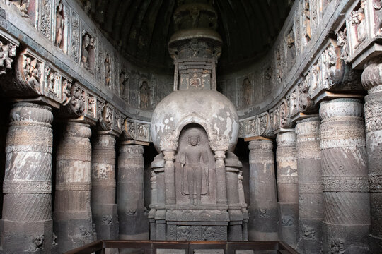 elaborate chaitya hall of ajanta cave 19 featuring a grand stone stupa with a standing buddha carved at its front, surrounded by richly ornamented pillars and detailed reliefs, part of the unesco worl
