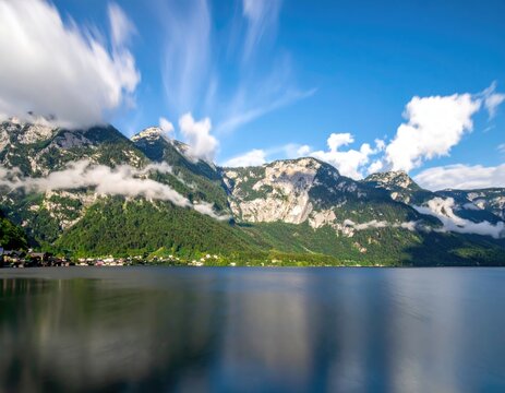 Serene lakeside view with mountainous backdrop and cloudy sky - Powered by Adobe