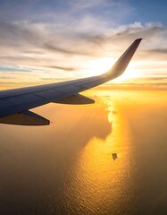 Obraz premium Airplane wing over sunset ocean