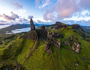 Rocky pinnacle on green hills, sky at dusk