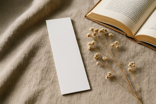 Blank white bookmark mockup on beige fabric background with dried flowers and an open book for branding or presentation concept layout design. Ai generative