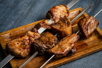 Grilled meat skewers on wooden board