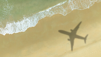 Aerial view of shadow passenger plane silhouette and sandy beach blue sea with waves at sea beach summer vacation sea travel concept	