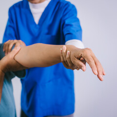 An Asian female nurse provides caring home care to an elderly woman, assisting with arm movement exercises, physical therapy,and rehabilitation to improve joint function, strength,overall well-being