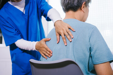 An Asian female nurse provides caring home care to an elderly woman, assisting with arm movement exercises, physical therapy,and rehabilitation to improve joint function, strength,overall well-being