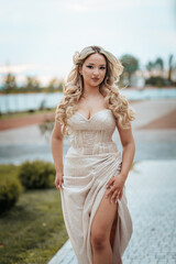 Radiant caucasian woman in a champagne satin prom dress with a high slit, posing outdoors
