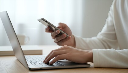 明るい部屋でPCとスマホを使う男性の手