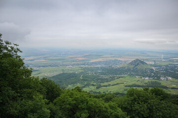 Fototapeta premium View of green hills and plains from the mountain top on a cloudy day