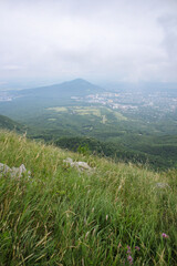 Mountain grass on the slope with a view of the green valley and city
