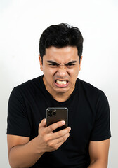 Portrait of a furious young man expressing rage and frustration while looking at his smartphone screen against a white background