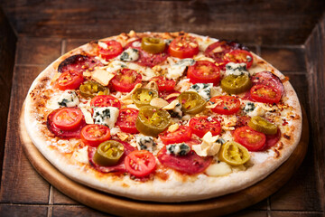 Pizza with salami, jalapeno pepper, cherry tomatoes and mozzarella cheese. Soft focus.	
