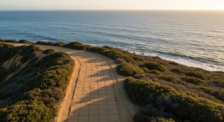 Coastal path winds along a clifftop overlooking a tranquil ocean