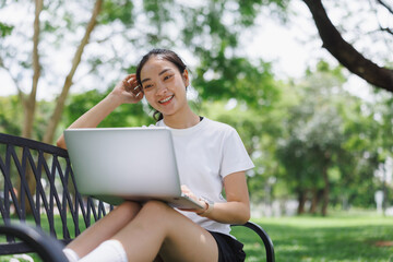 Young asian woman working on laptop in park