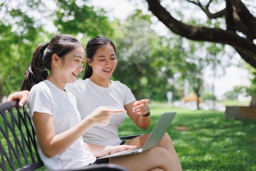 Friends enjoying leisure time together with laptop in park