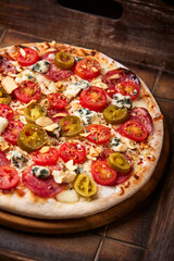 Pizza with salami, jalapeno pepper, cherry tomatoes and mozzarella cheese. Soft focus.	