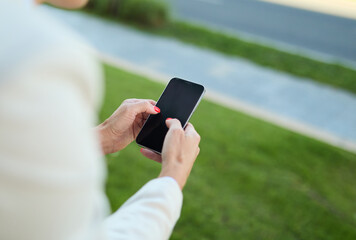 Closeup of a phone and phone screen, young businesswoman woman using a smartphone mobile phone walking down the street, surrounded by moder corporate office buildings
