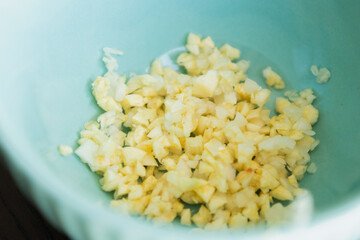 minced garlic in small blue bowl close up
