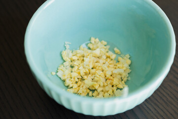 minced garlic in small blue bowl close up