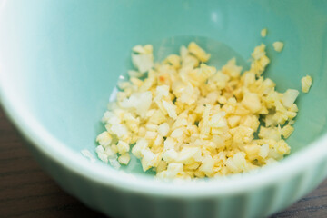 minced garlic in small blue bowl close up