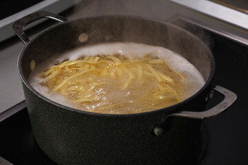 A close-up stock photo of fresh tagliatelle pasta boiling in a pot